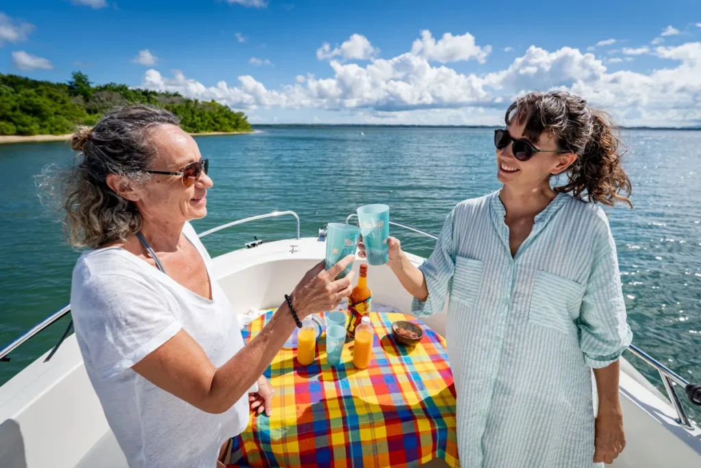 Deux passagères trinquent à bord du bateau Mana Ti Boat lors d’une sortie sur le lagon du Grand Cul-de-Sac Marin