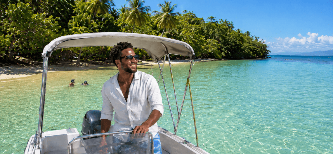Location de bateau en Guadeloupe dans le lagon turquoise de l’îlet Gosier, avec plage de sable, cocotiers et sortie en mer en famille